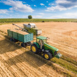 Combine Harvester Pouring Grain into Trailer Towed by Tractor